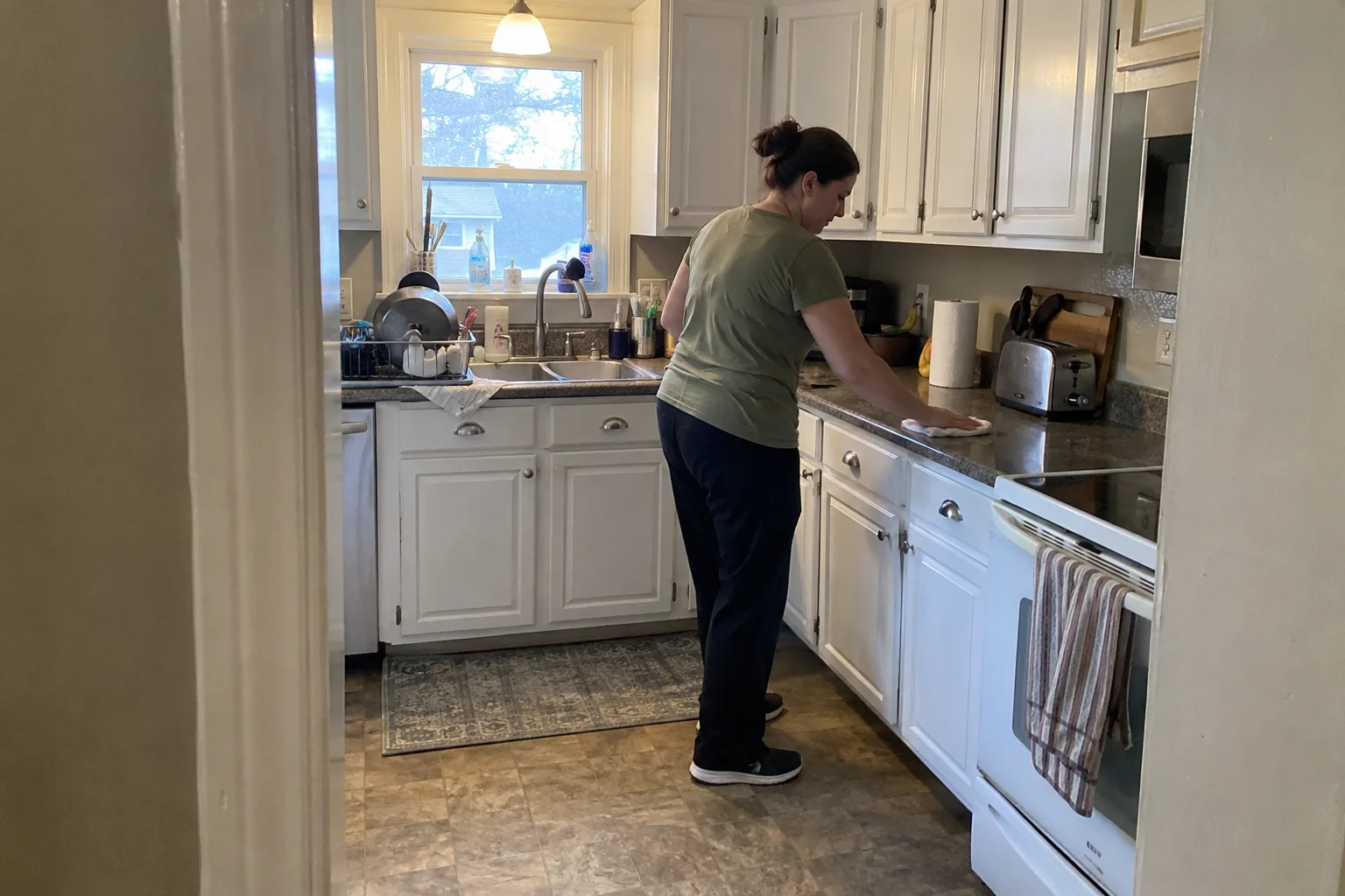 Professional cleaner wiping a kitchen countertop with a microfiber cloth