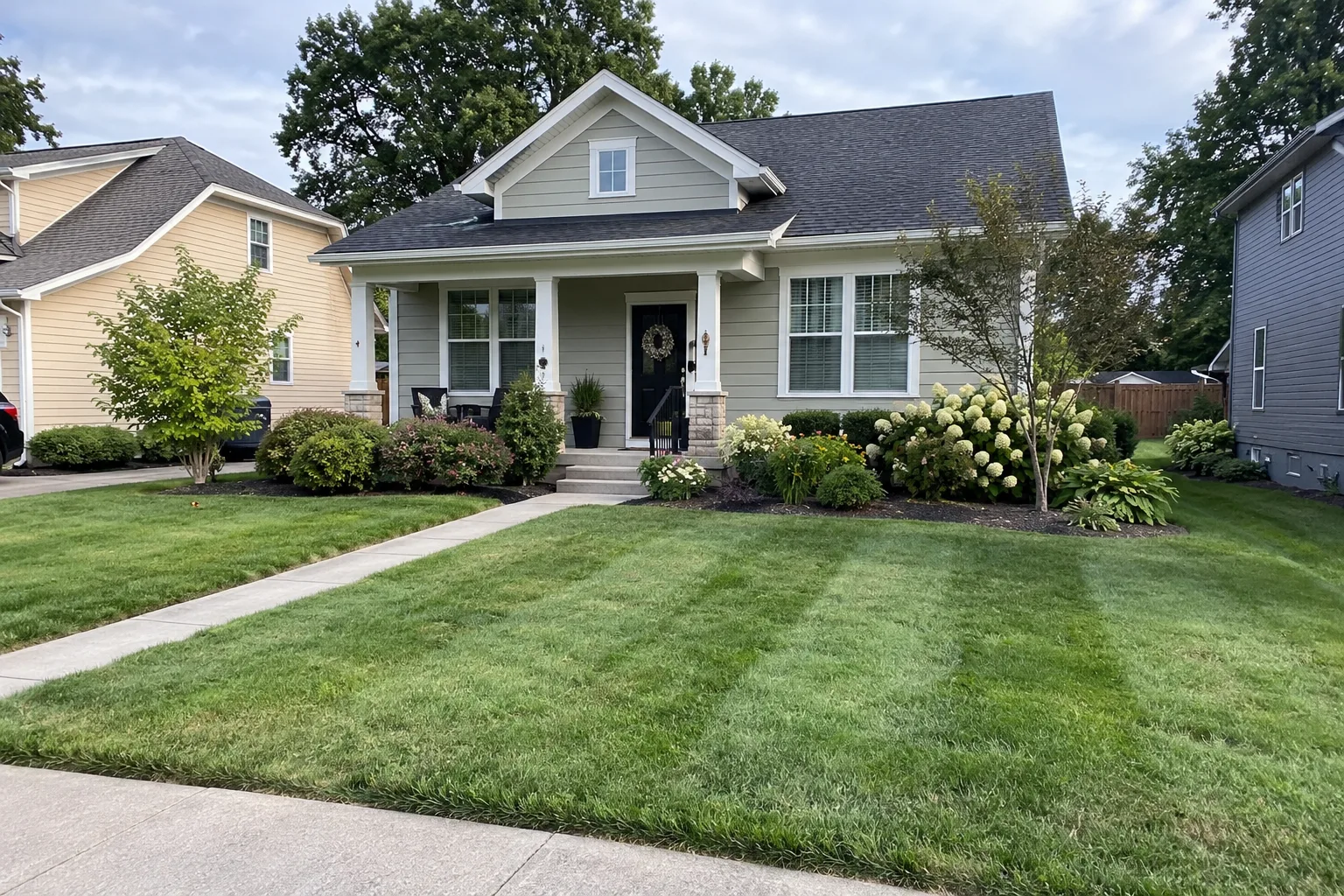 A well-kept home with a freshly mowed lawn, flower beds, and a welcoming front porch